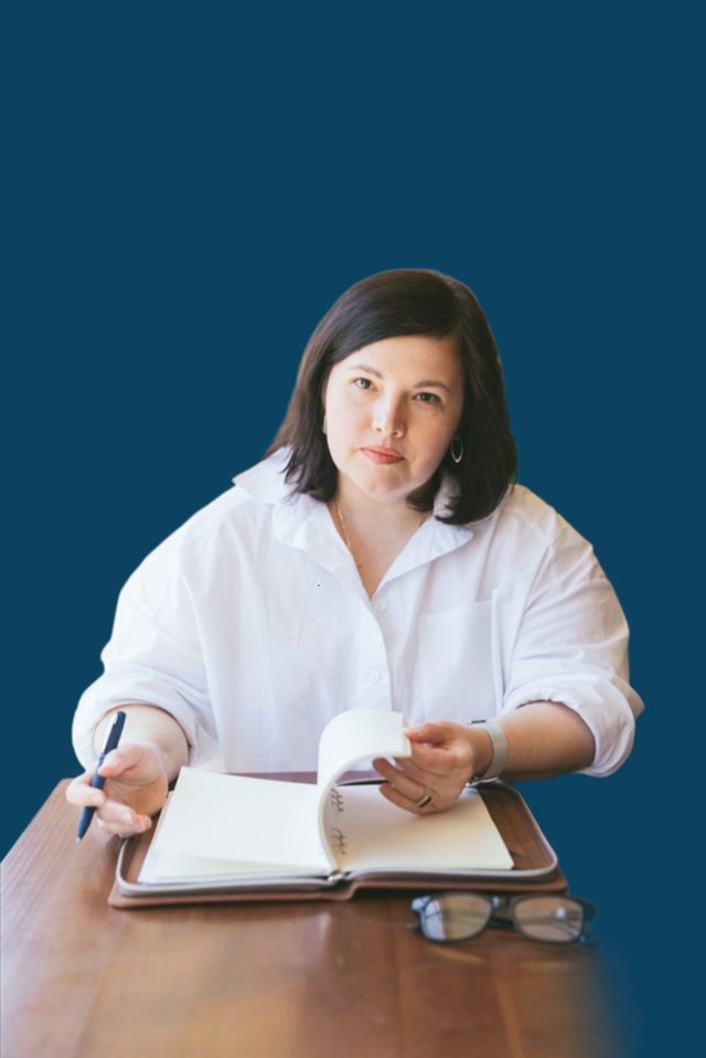 Ірина Савенко за робочим столом з блокнотом і ручкою